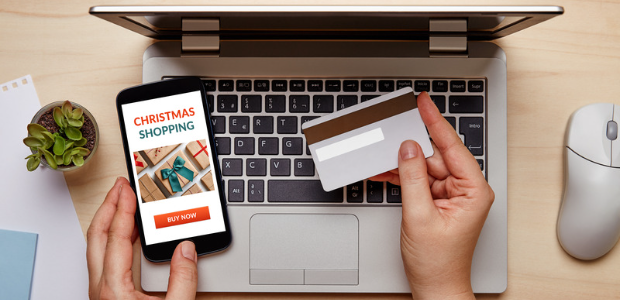 Person holding credit card while looking at a smartphone that says Christmas Shopping with a Buy Now button.